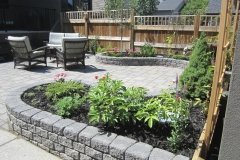 decorative stone wall with assorted perennials and black mulch