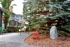 Paving stone patio with cedar mulch and a decorative address boulder